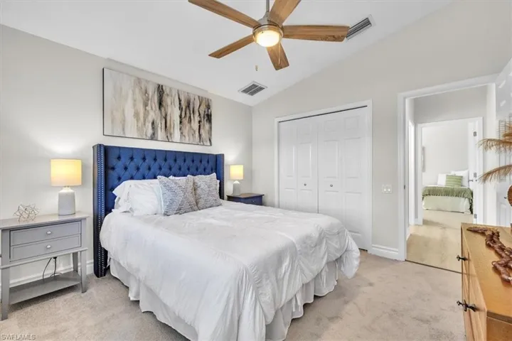 Bedroom featuring light colored carpet, vaulted ceiling, a closet, and a ceiling fan