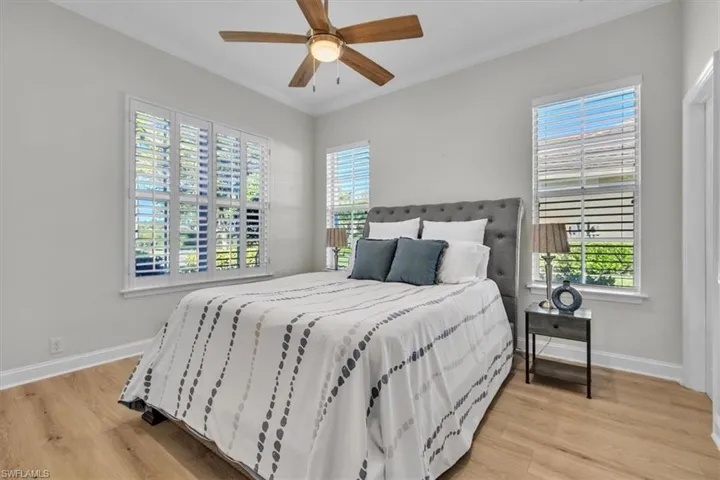 Bedroom with ceiling fan, multiple windows, crown molding, and light wood-type flooring