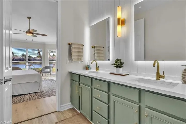 Full bathroom with ornamental molding, double vanity, light wood-type flooring, a ceiling fan, and ensuite bathroom