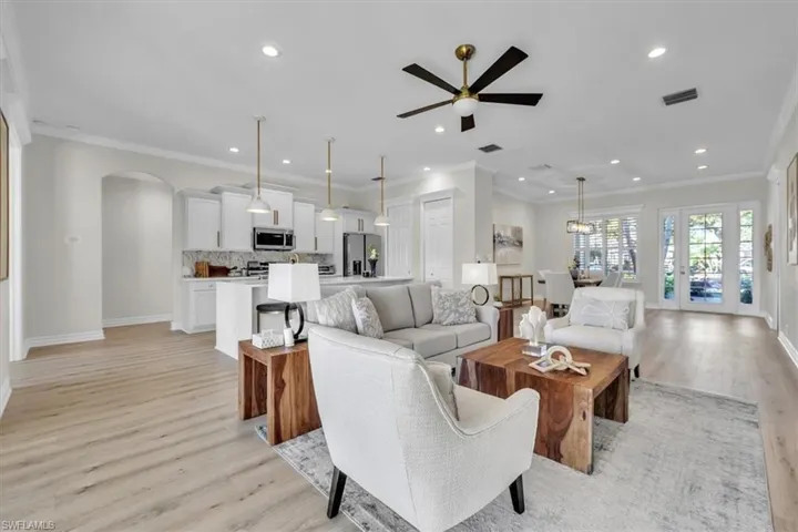 Living room featuring light wood-style flooring, ceiling fan, ornamental molding, recessed lighting, and arched walkways