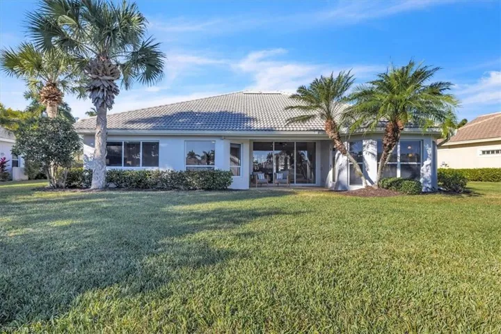 Rear view of house with a tiled roof, a yard, stucco siding, and a sunroom