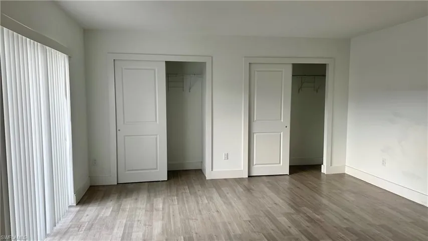 Unfurnished bedroom with multiple closets and wood finished floors