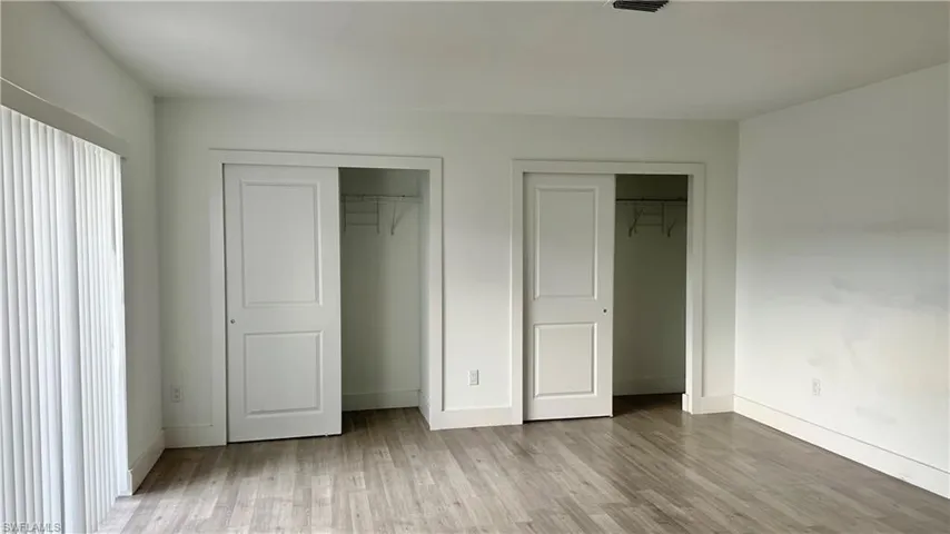 Unfurnished bedroom with two closets and wood finished floors