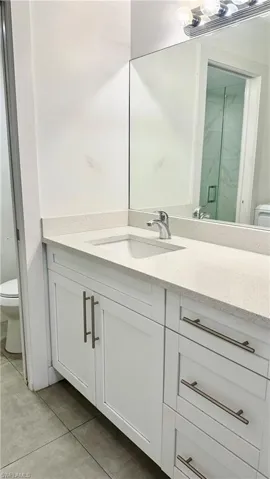 Full bathroom with vanity, light tile patterned floors, and a marble finish shower