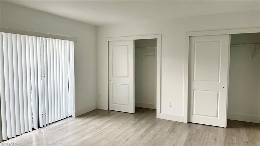 Unfurnished bedroom with two closets and light wood-style flooring
