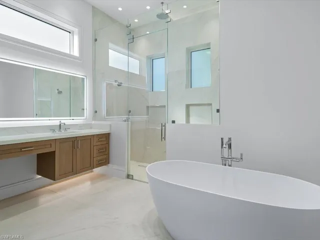 Master Bathroom featuring vanity and plus walk in shower his and her water closets