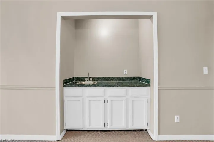 Bar with light carpet, sink, and white cabinets