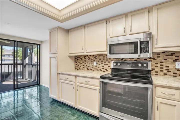 Kitchen with appliances with stainless steel finishes, light stone countertops, cream cabinetry, decorative backsplash, and ornamental molding
