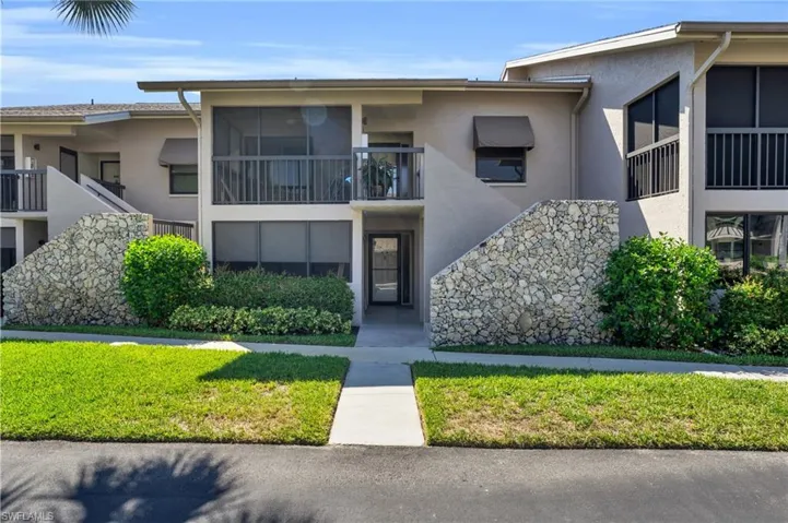 View of front of house featuring a balcony and a front yard