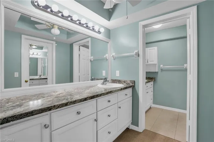 Bathroom featuring tile patterned flooring, a tray ceiling, ceiling fan, and vanity