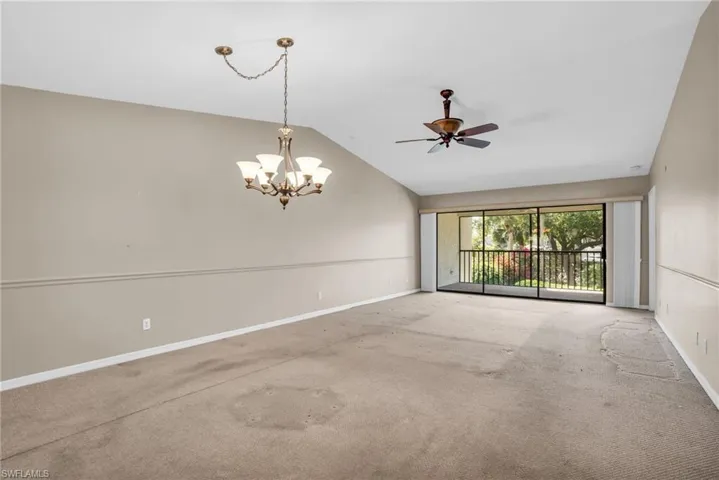 Spare room with ceiling fan with notable chandelier, lofted ceiling, and carpet