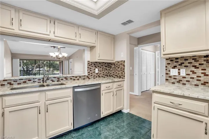 Kitchen featuring a notable chandelier, tasteful backsplash, sink, stainless steel dishwasher, and carpet floors