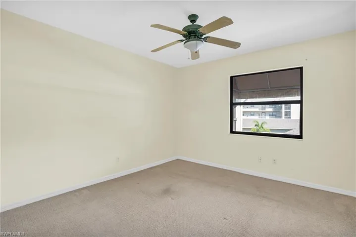Carpeted empty room featuring ceiling fan