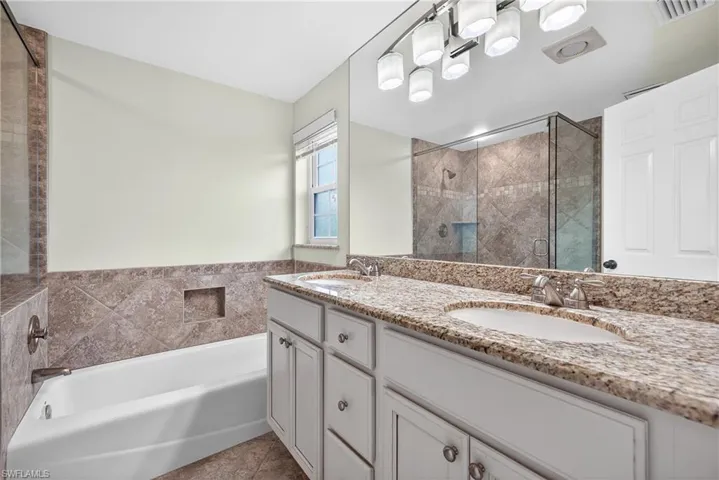 Bathroom with double vanity, a bath, and a stall shower
