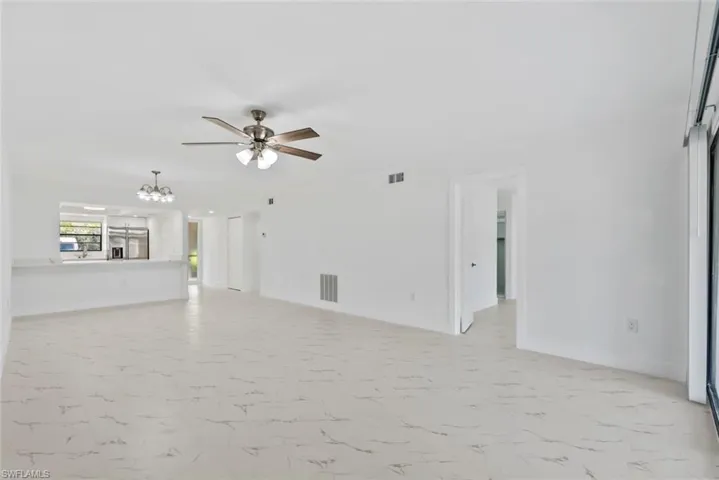 Unfurnished living room with a ceiling fan, suspended lighting, and light marble finish floors