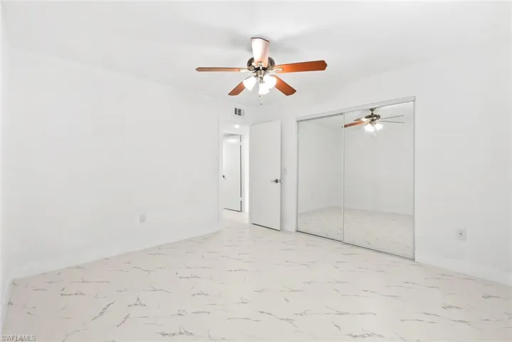 Unfurnished bedroom with ceiling fan, light marble finish floors, and a closet
