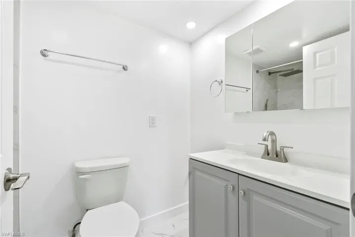 Bathroom with vanity, light marble finish flooring, a marble finish shower, and recessed lighting