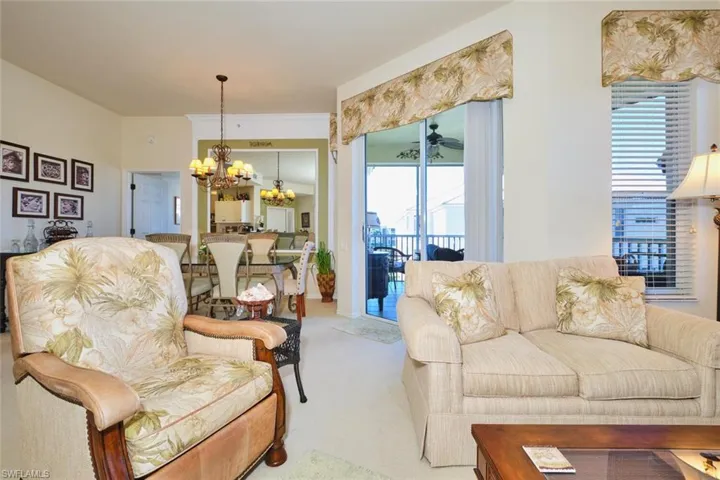 Living area with suspended lighting, carpet flooring, and a ceiling fan