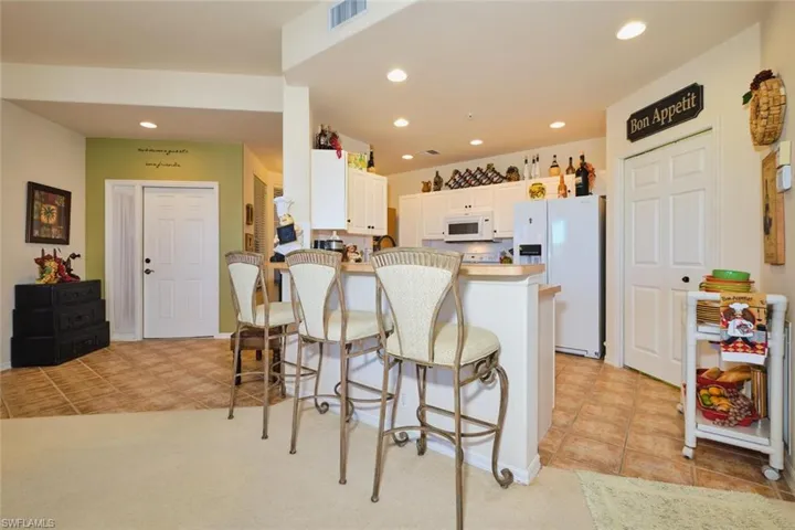 Kitchen with white cabinets, a breakfast bar area, white appliances, a peninsula, and recessed lighting