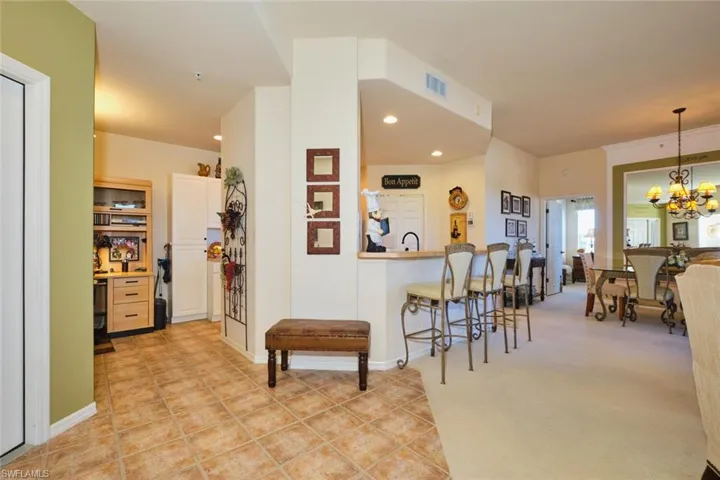 Kitchen with a breakfast bar area, a chandelier, and light colored carpet