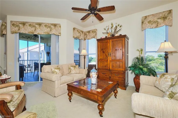 Carpeted living area featuring ceiling fan and baseboards
