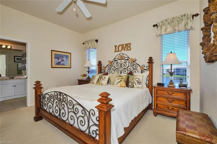 Bedroom featuring light carpet, ensuite bathroom, and a ceiling fan