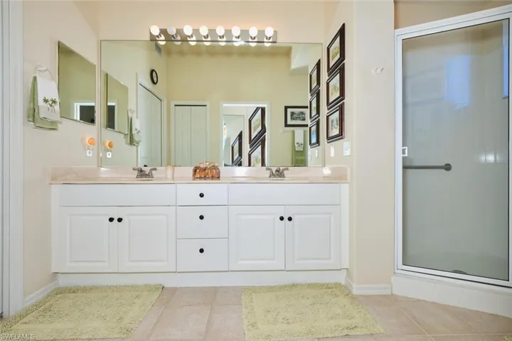 Bathroom featuring double vanity, a stall shower, and light tile patterned floors