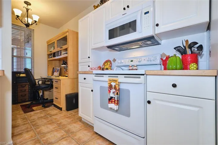 Kitchen with white appliances, light countertops, white cabinets, and an office area