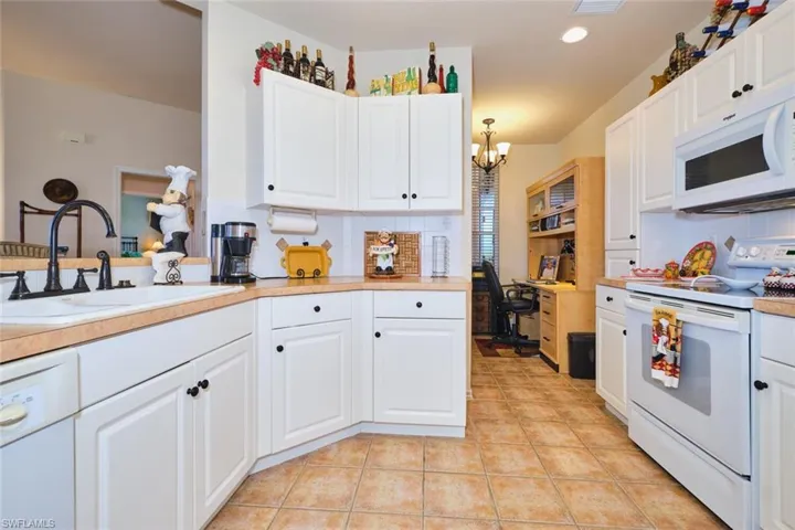Kitchen featuring white appliances, white cabinetry, light countertops, decorative backsplash, and light tile patterned floors