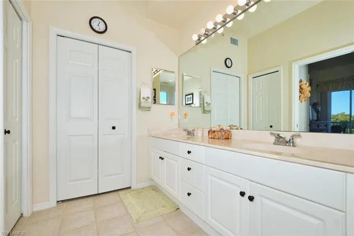 Full bathroom featuring a closet, double vanity, and light tile patterned floors