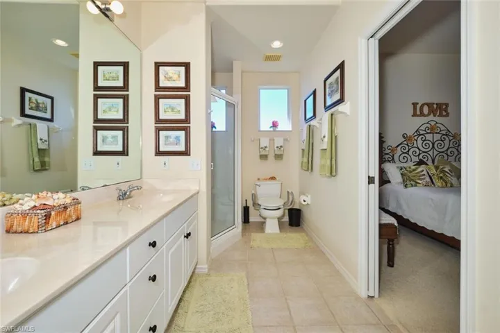 Ensuite bathroom featuring a stall shower, double vanity, and light tile patterned floors