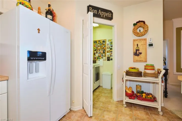 Kitchen featuring white fridge with ice dispenser and washer / dryer