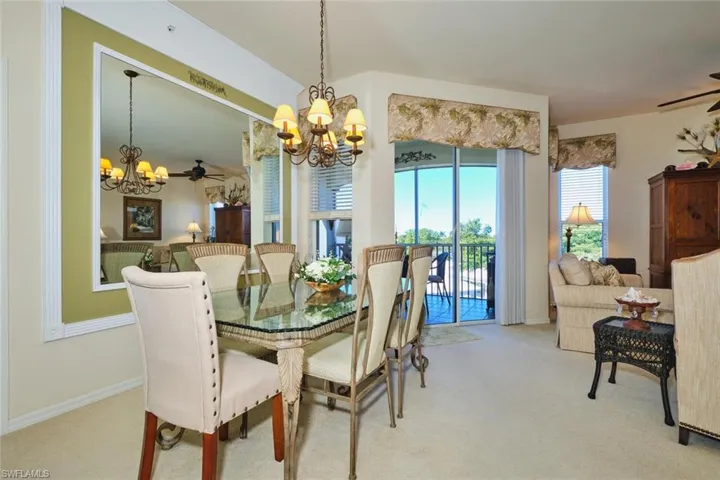 Dining area featuring a ceiling fan, a chandelier, and light colored carpet