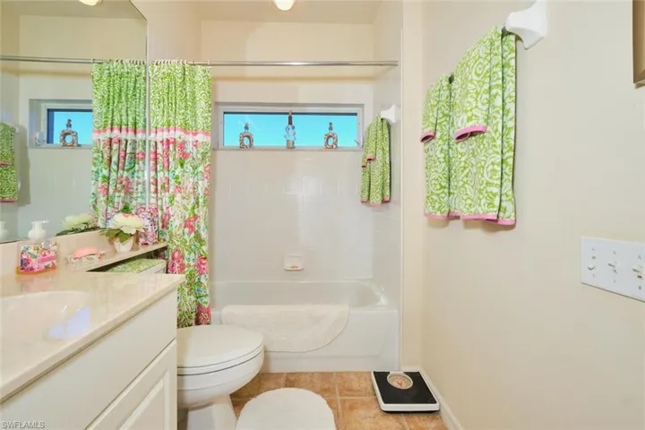 Full bath with shower / bath combination with curtain, vanity, and light tile patterned floors