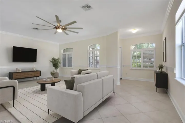 Living area featuring light tile patterned floors, ornamental molding, and ceiling fan