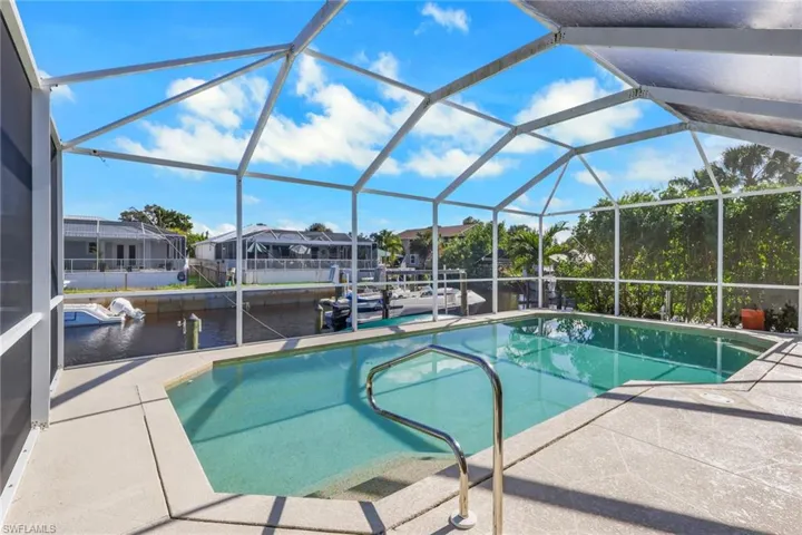 Outdoor pool featuring a lanai, a sunroom, a water view, and a patio