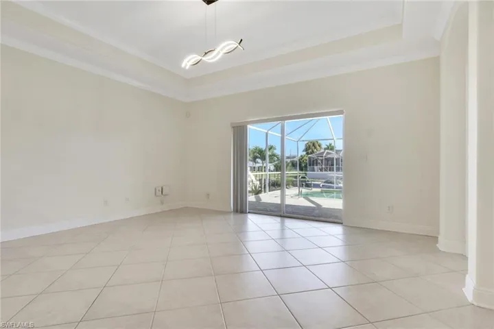 Empty room with a sunroom, a tray ceiling, ornamental molding, and light tile patterned flooring