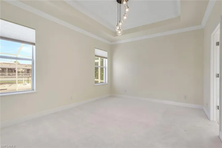 Empty room featuring crown molding, light carpet, and a raised ceiling