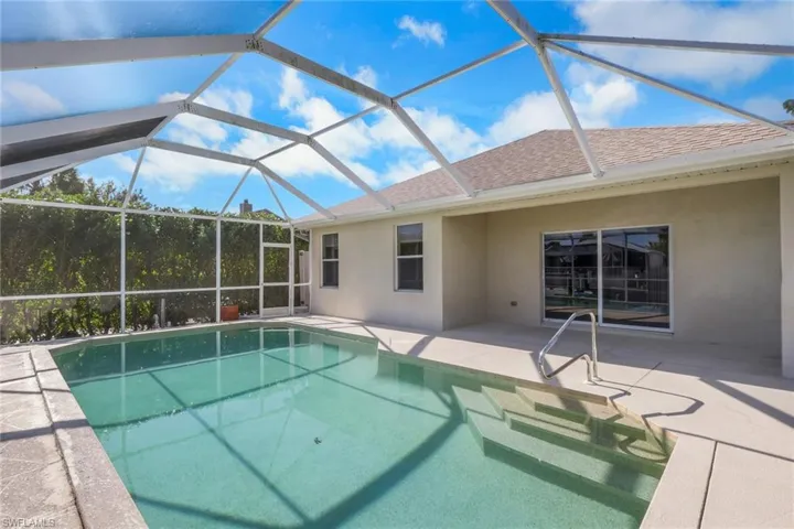 Outdoor pool featuring a sunroom, a patio, and glass enclosure