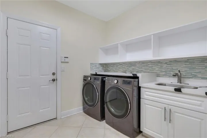 Laundry room with washing machine and clothes dryer, light tile patterned flooring, and cabinet space
