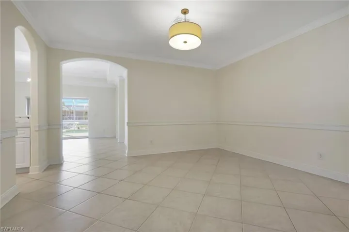Spare room featuring arched walkways, light tile patterned floors, and crown molding
