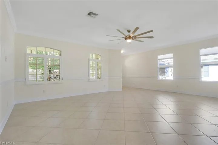 Spare room with crown molding, ceiling fan, and light tile patterned floors