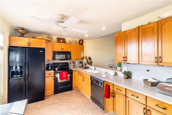 Kitchen featuring decorative backsplash, ceiling fan, sink, and black appliances