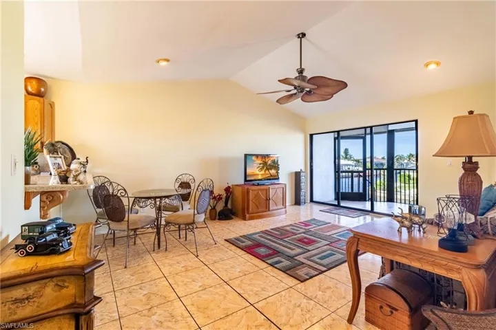 Tiled living room with ceiling fan and vaulted ceiling