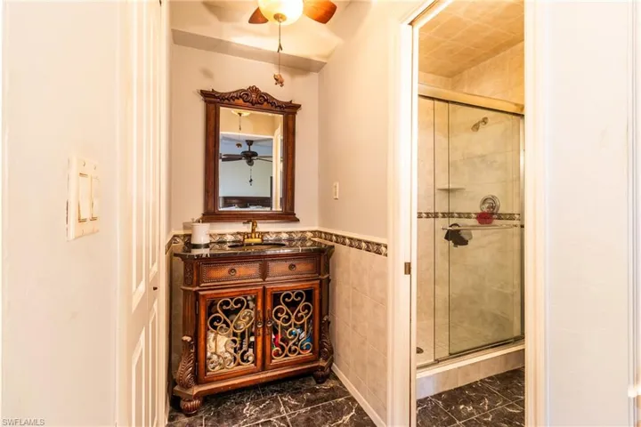 Bathroom with vanity, an enclosed shower, and tile walls