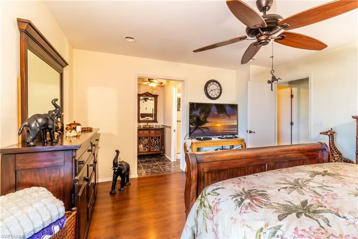 Bedroom featuring connected bathroom, ceiling fan, and dark hardwood / wood-style flooring