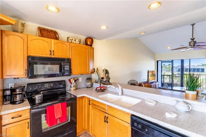 Kitchen featuring ceiling fan, sink, tasteful backsplash, vaulted ceiling, and black appliances