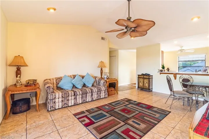 Living room with ceiling fan and lofted ceiling
