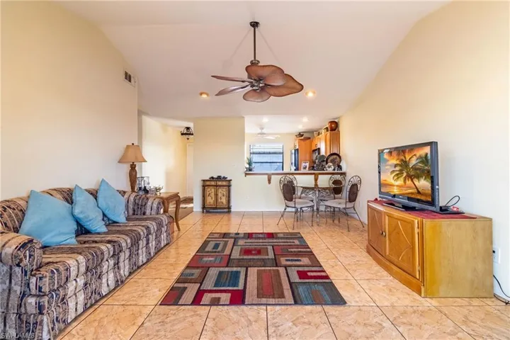 Tiled living room with ceiling fan and lofted ceiling