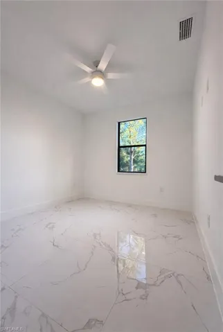 Spare room with light marble finish floors and ceiling fan